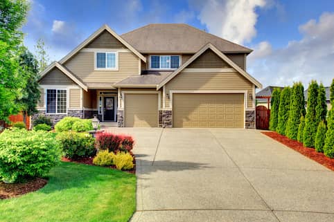 Tan split brick home with red mulch.