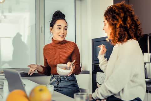 Two women talking in a kitchen.