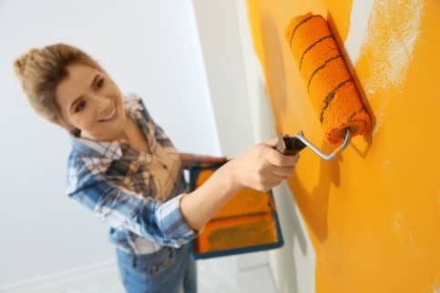 woman painting wall orange