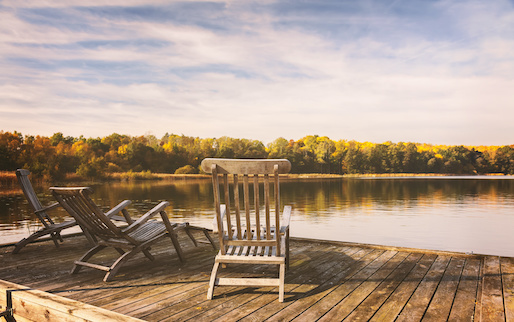 Deck chairs on dock overlooking lake of vacation home. 