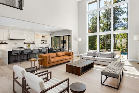 Minimalist staged kitchen dining living room in open concept home with large windows.