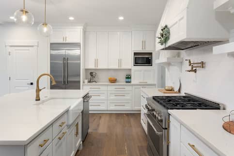 White Kitchen With Gold Handles And Stainless Steel Appliances