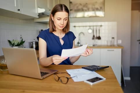 woman in front of laptop looking at paperwork