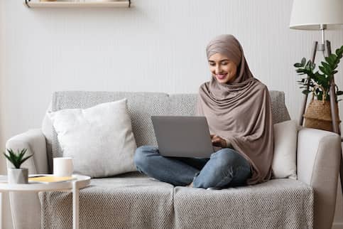 Woman In Hijab On Couch With A Laptop