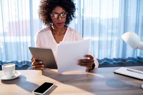 woman reading document and holding ipad