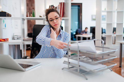 Woman doing paperwork and talking on the phone.