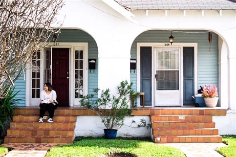 Woman sitting on porch of house.