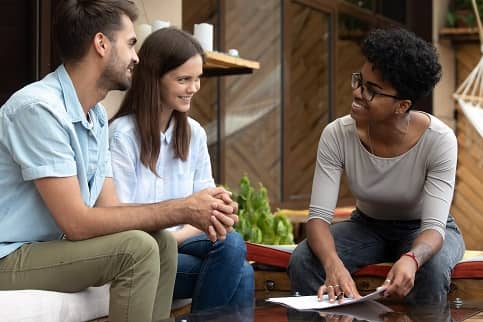 Young couple discussing contract with female expert.