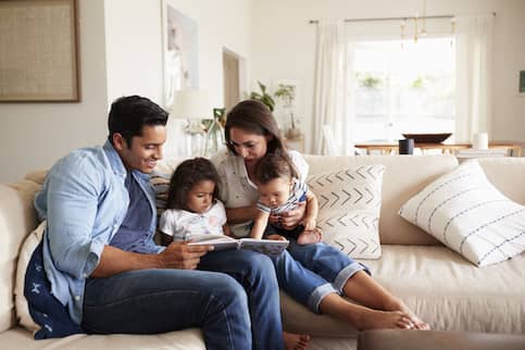 Young family reading together on the couch.