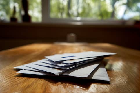 Mail piled onto wood table.