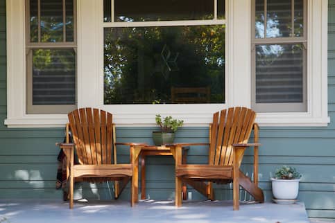 Front porch of house with wood chairs.