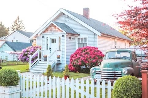 Quaint suburban home with hedges and pink flowers.