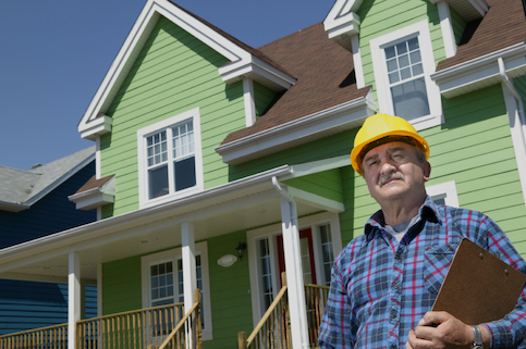 Construction worker standing in front of a green house.