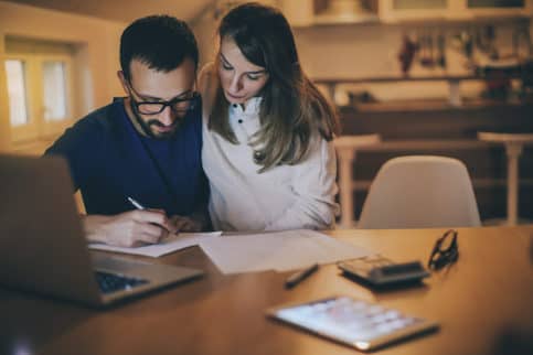 Young couple looking at a budget together on a laptop at home.
