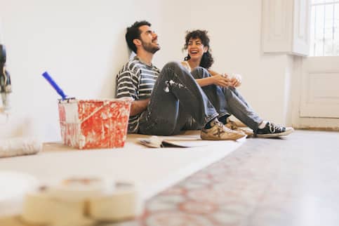 Young couple resting on their floor after painting their wall.