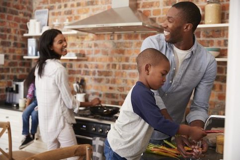 African American family of three in their brick wall kitchen.