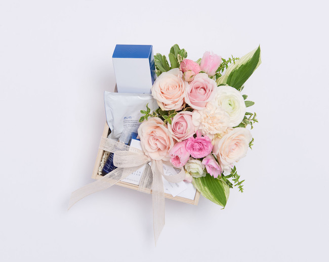 Bedroom gift basket containing pink flowers and aromatherapy items.