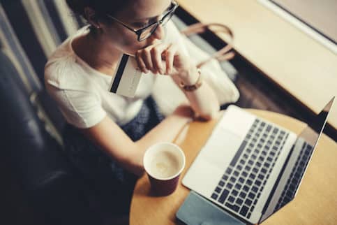 Woman shopping online on laptop at cafe.