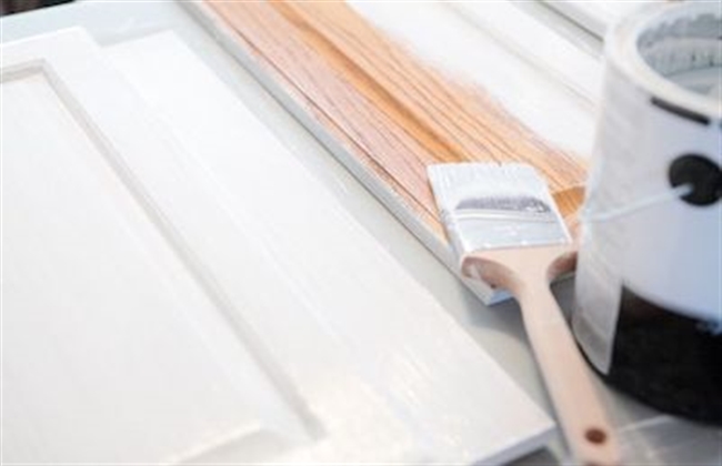 Close up of a half painted white cabinet door.