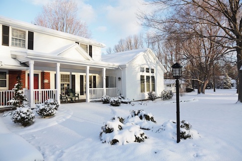 Large house with front yard both covered in snow.