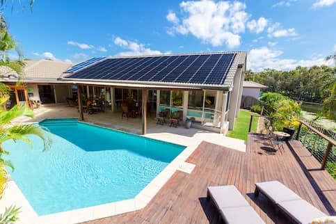 House with a large pool and solar panels across the roof.