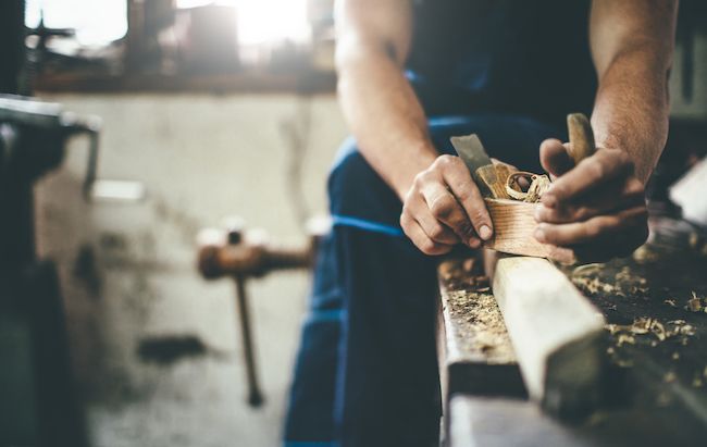 Man sanding wood in his workshop.