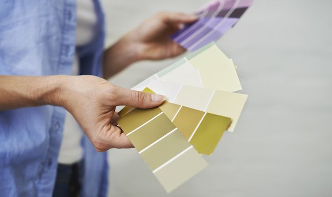 Close up of hands holding paint swatches.