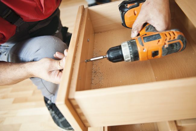 Close up shot of someone using a drill to reassemble their cabinets.