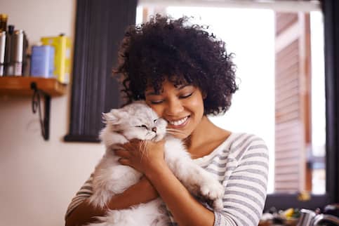 Young woman holding her cat affectionately.