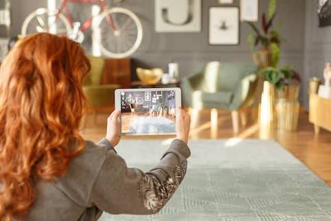 Young woman with red hair photographing her house for a house listing.