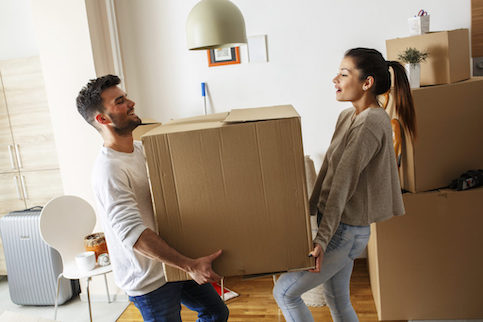 Young couple moving box into new home.