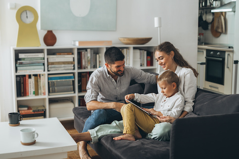 Parents reading with child on couch in living room.