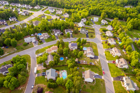 Aerial view of neighborhood near small forest.