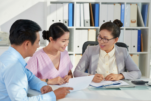 Asian couple looking over documents with an agent.