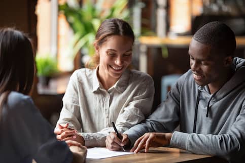 Young couple speaking with a business woman at a desk.