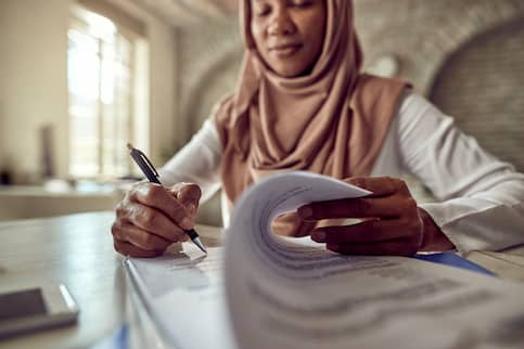 Muslim woman signing papers.
