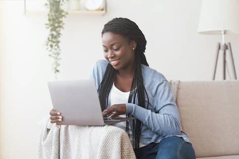 Young Black Woman Working With Laptop On Sofa