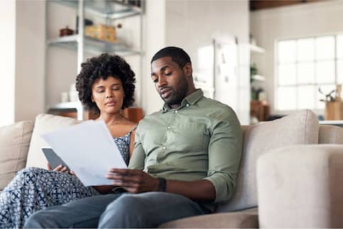 man and woman sitting on couch reading documents