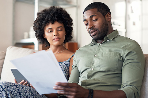 Couple looking over documents while sitting on the couch.