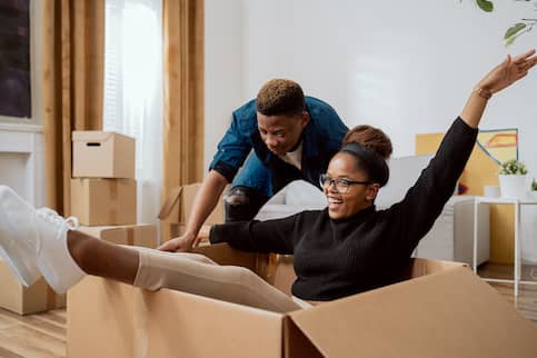 African-American couple unpacking boxes and relaxing.