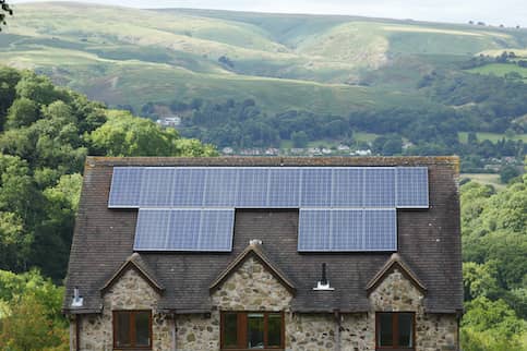 Off grid stone house in rolling hills with solar panels.