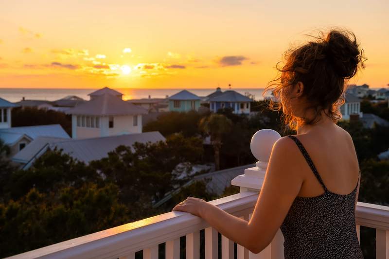 A woman looks from the balcony of her Florida home at the ocean.
