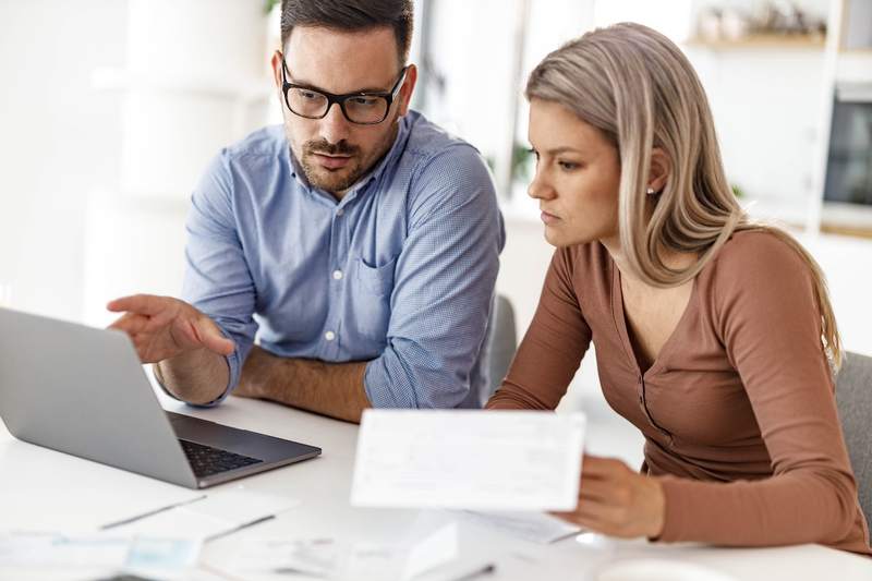 A man and a woman sitting in front of a laptop calculate loan interest.