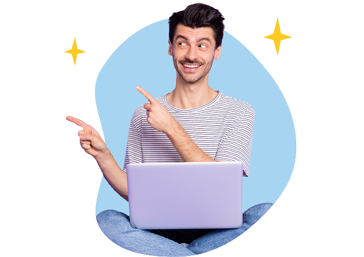 Smiling man sitting cross-legged with a laptop and pointing at editorial guidelines with both hands.